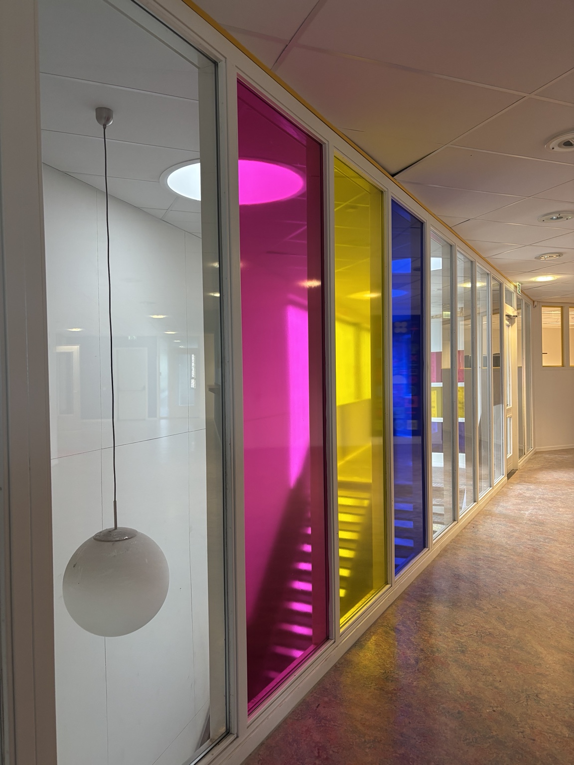 Gang met glasvlakken in transparant roze, geel en blauw